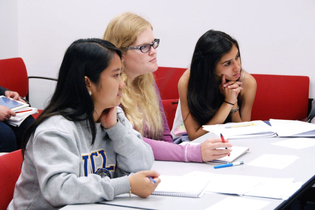 Students listening in a lecture session with their notes open.