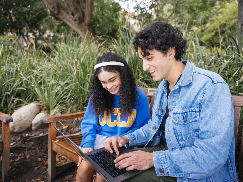 Photo of two students looking at a laptop at the Botanical Gardens