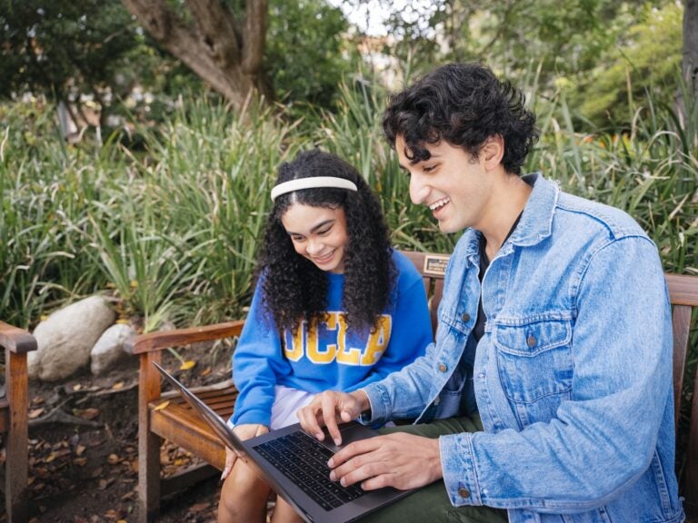 Photo of two students looking at a laptop at the Botanical Gardens