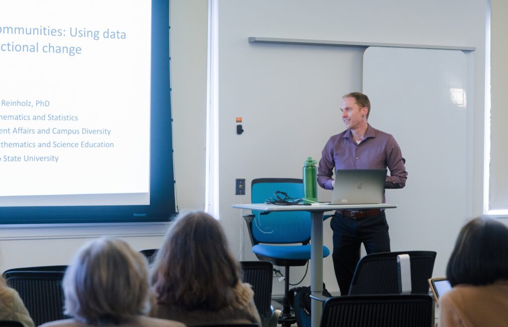 Image of a professor in front of a projector with text