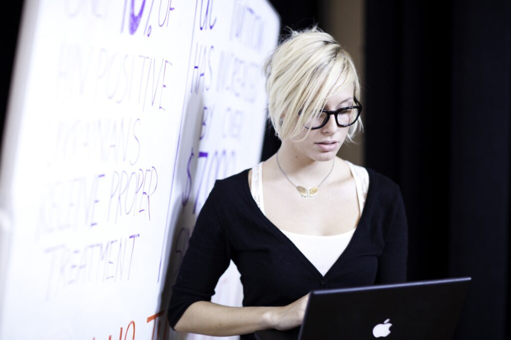 Photo of student with a laptop near a whiteboard