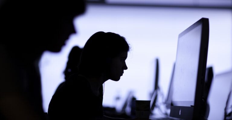 Students working at large computer monitors Working on computers.