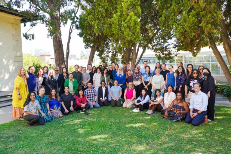 Group of instructors and Summer Institute facilitators smiling on the grass outside Hershey Hall