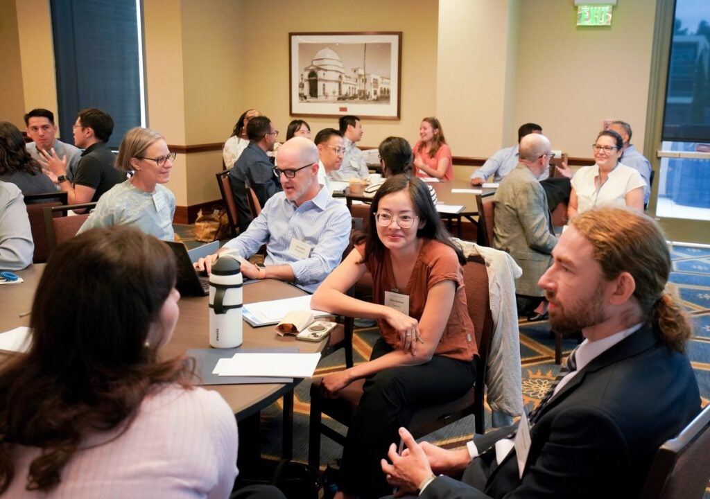 Attendees talking at a table during the New Instructor Teaching Institute.