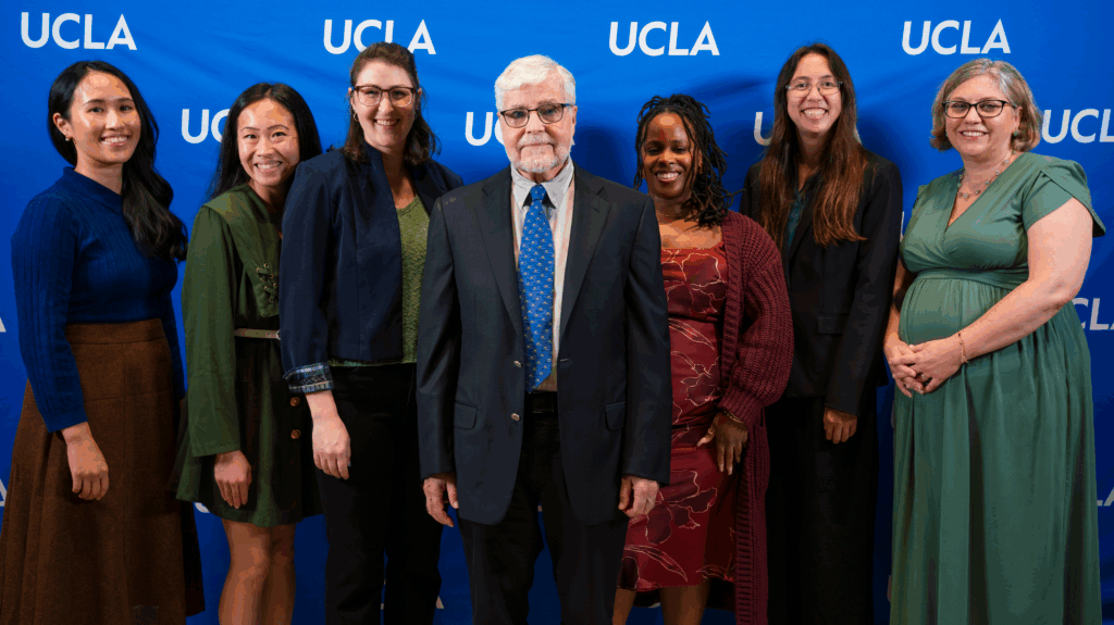 Vanessa Pooudomsak, Ivy Kwok, Caitlyn Fick, Vice Chancellor Michael Levine, Lynette Dixon, Alexis Korb, and Vice Provost Erin Sanders O'Leary against a blue UCLA background.