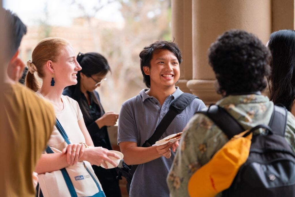 Graduate students in a group smiling at one another on a balcony