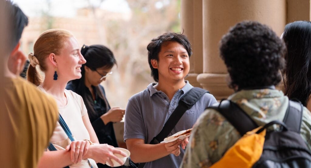 Graduate students smiling in a group at one another