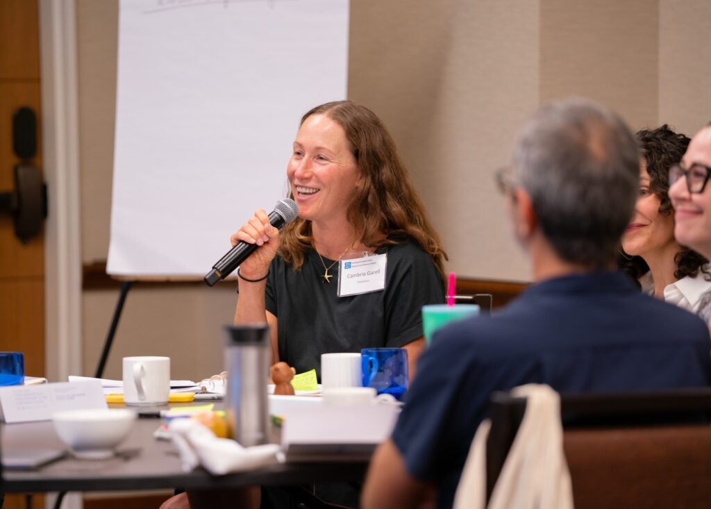 Cambria Garrell speaks into a microphone sitting at a table