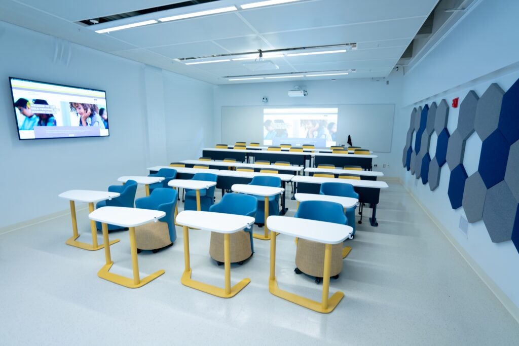 Empty white classroom containing blue chairs and moveable desks
