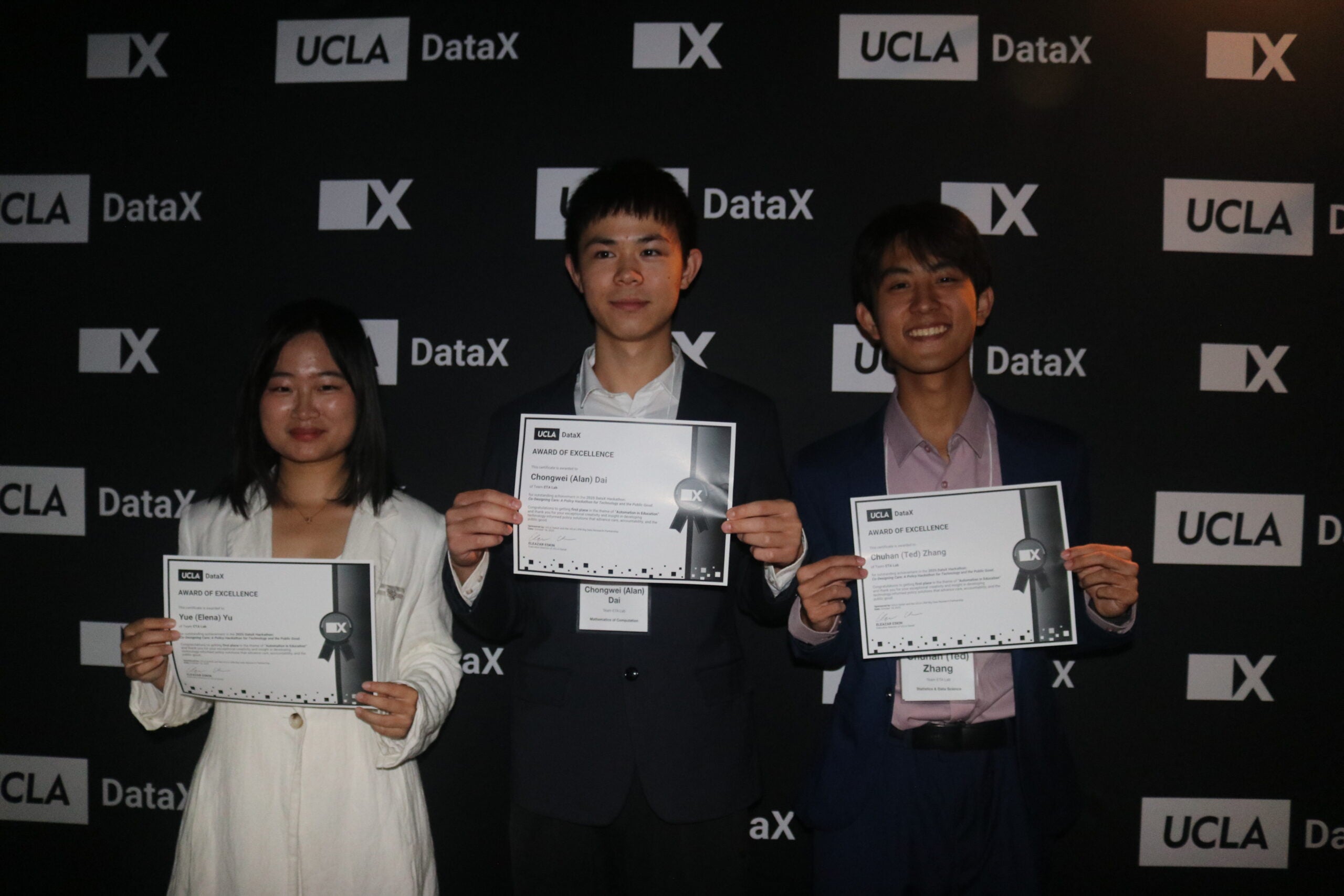 Individuals holding certificates in front of a DataX background