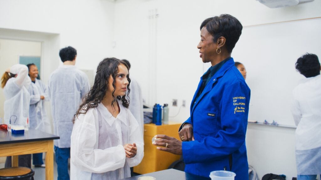 Instructor and student in discussion in a lab wearing lab coats