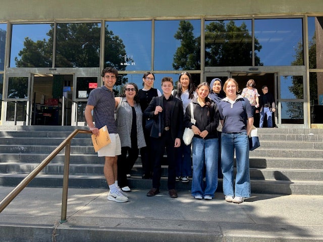Students and an instructor standing outside of a courthouse smiling.