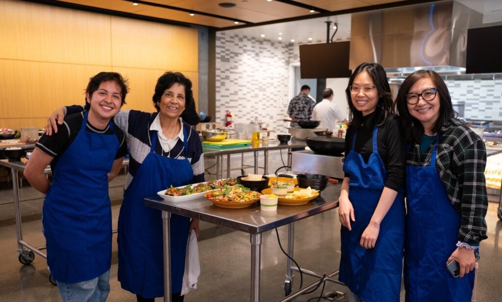 Instructors and graduate students smiling in front of their dishes made in the Tipuana Teaching Kitchen