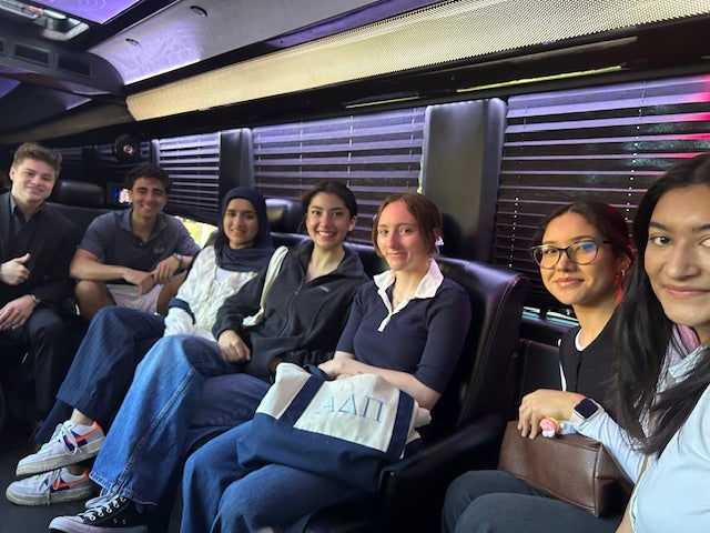 Students seated in the interior of a bus smiling at the camera