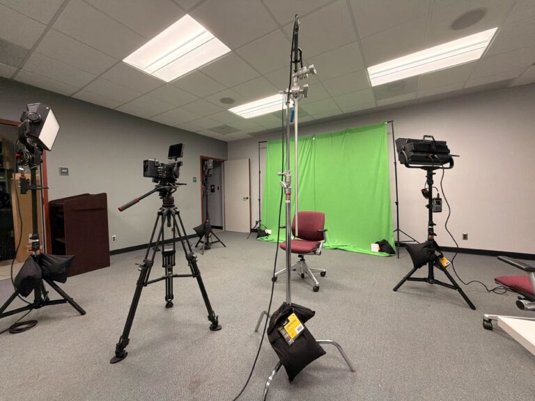 Immersive media production studio with green screen and cameras.