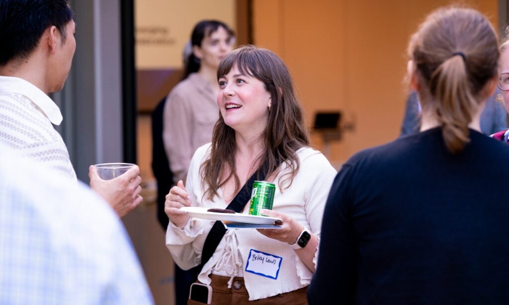 Briley Lewis stands in a group of academic staff in conversation.