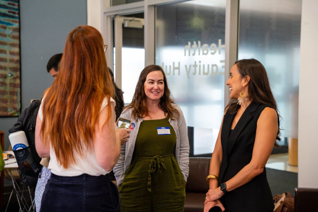 Angie Denisse Otiniano Verissimo speaks with with two event attendees in the Health Equity Lab.