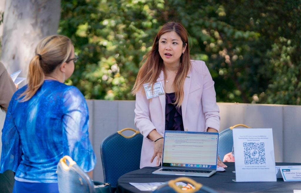 A TLC staff member speaks with a Symposium attendee during the tech exposition.