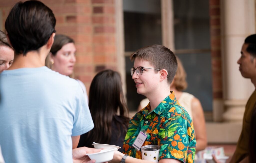 A postdoctoral scholar stands in conversation with other event attendees