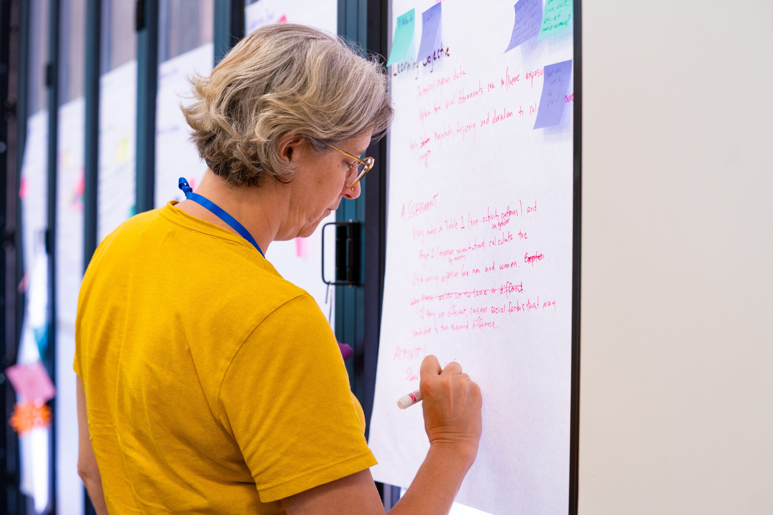 Instructor writes notes on a large piece of paper on the wall.