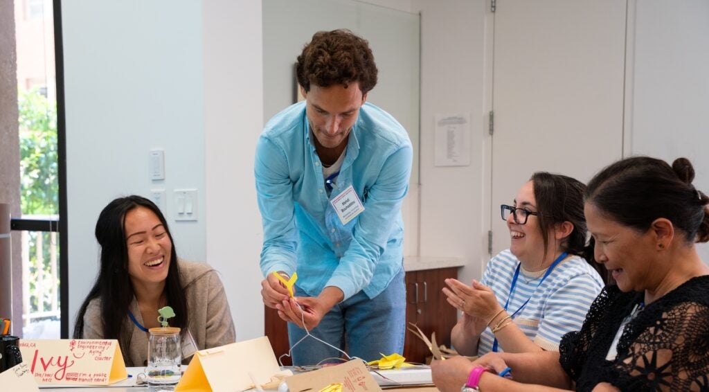 Instructors construct mobiles together at a table.