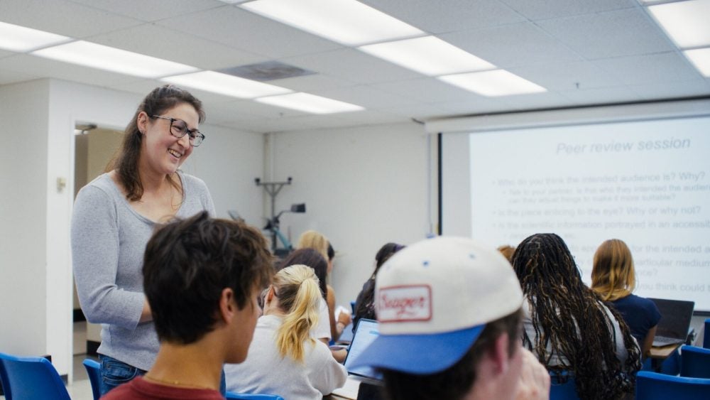 Graduate instructor speaks to students seated in a classroom
