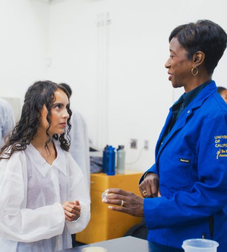 Instructor and student in discussion in a lab wearing lab coats