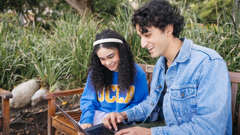 Photo of two students looking at a laptop at the Botanical Gardens