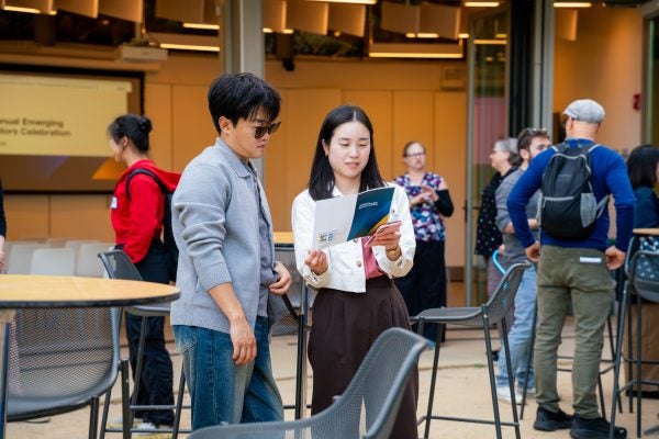 Graduate students gathered outside of La Kretz auditorium reviewing an event program