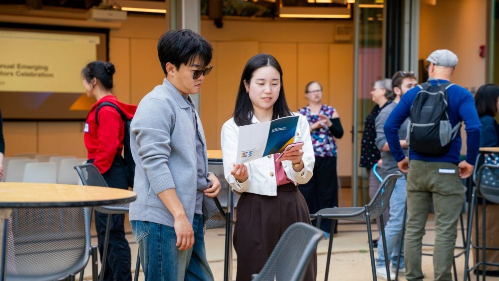 Graduate students gathered outside of La Kretz auditorium reviewing an event program