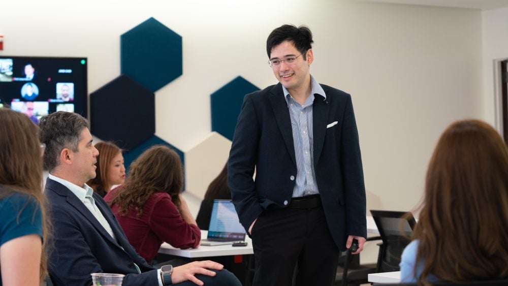 Andrew Estrada Phuong stands in a classroom talking to participants at the scholarly teaching seminar.