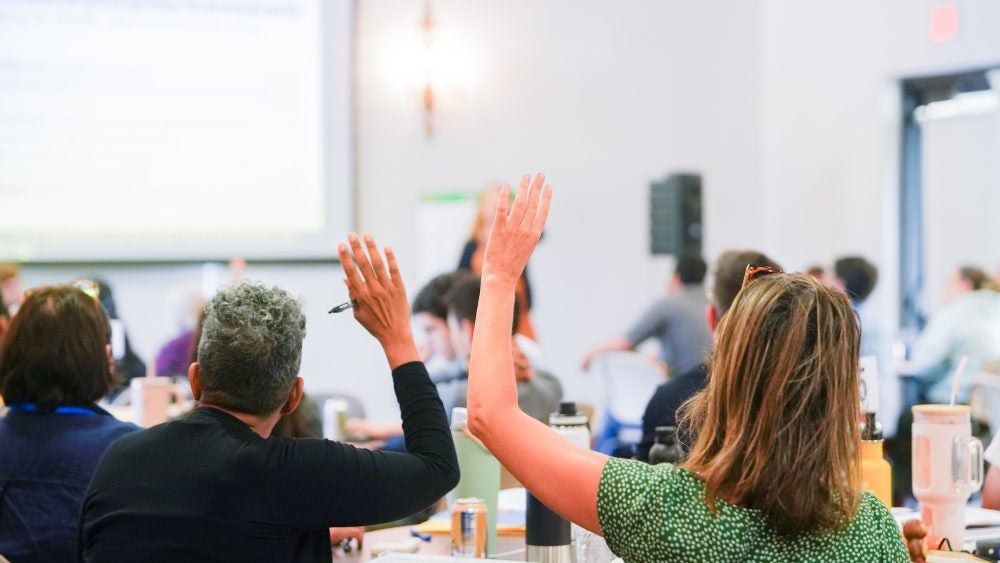 Backs of instructors with raised hands in a classroom
