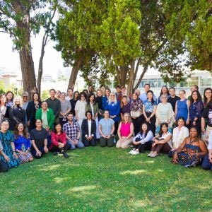 Group of instructors and Summer Institute facilitators smiling on the grass outside Hershey Hall