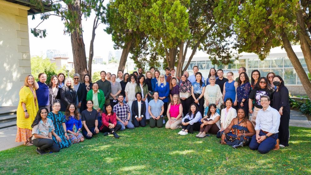 Group of instructors and Summer Institute facilitators smiling on the grass outside Hershey Hall
