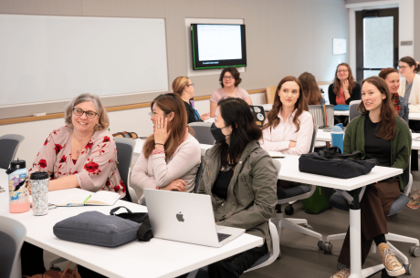 Vice Provost Erin Sanders O'Leary seated at a lecture hall table talking with TLC staff