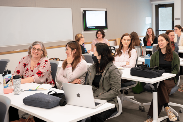 Vice Provost Erin Sanders O'Leary seated at a lecture hall table talking with TLC staff