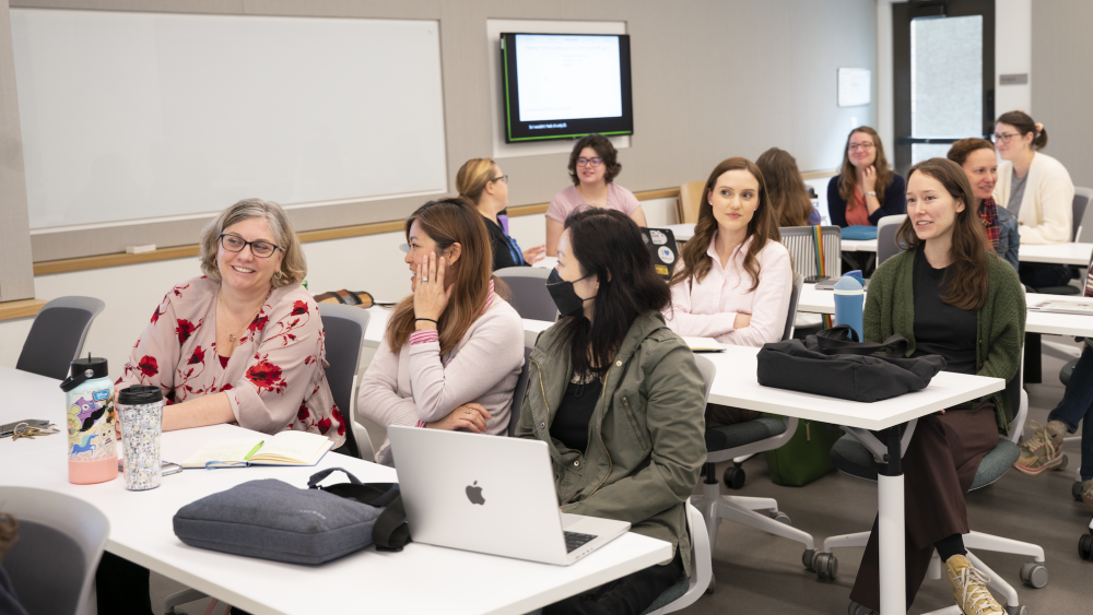 Vice Provost Sanders O'Leary seated at a lecture hall table talking with TLC staff