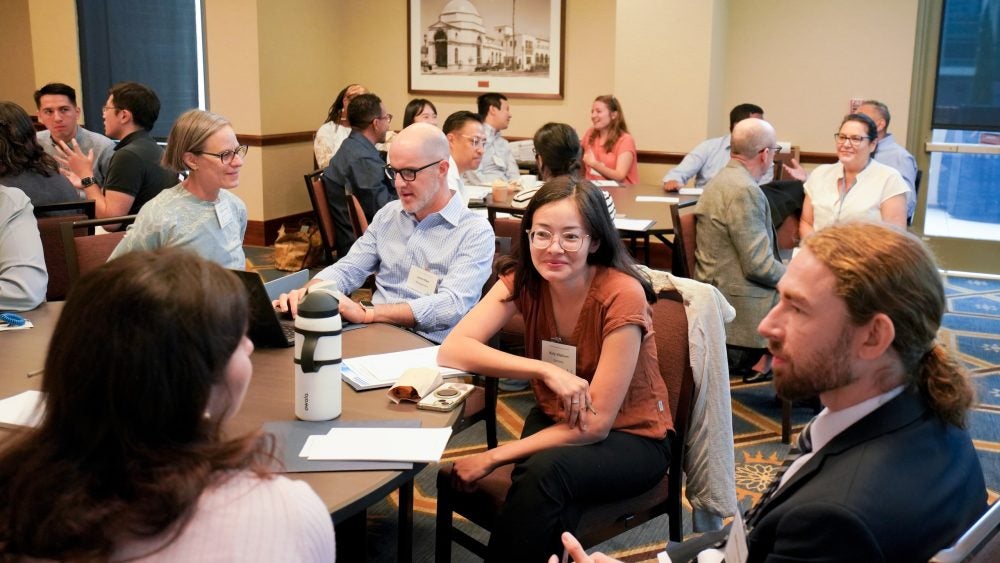 Attendees talking at a table during the New Instructor Teaching Institute.