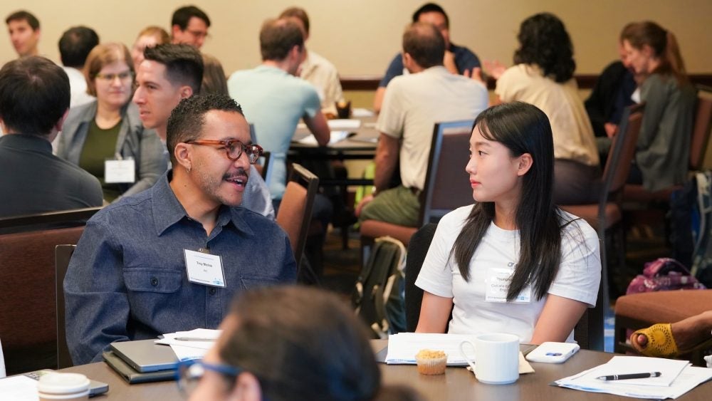 Two Instructors sitting at a table talking during the New Instructor Teaching Institute.