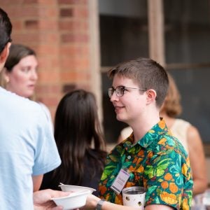 A postdoctoral scholar stands in conversation with other event attendees