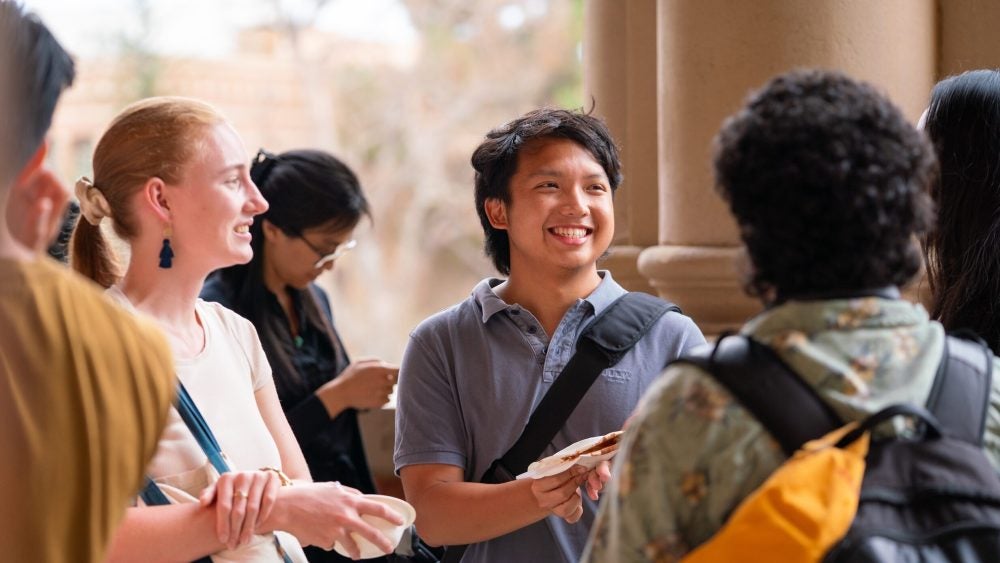 Graduate students smiling in a group at one another