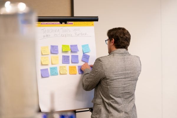 Instructor at DaD Faculty Fellows Kickoff event places notecards on a whiteboard