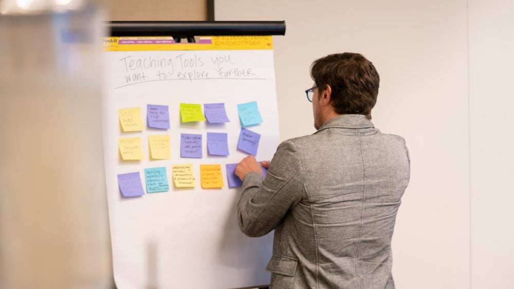 Instructor at DaD Faculty Fellows Kickoff event places notecards on a whiteboard