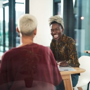 Cropped shot of an attractive young businesswoman sitting and laughing with her female colleague in the office