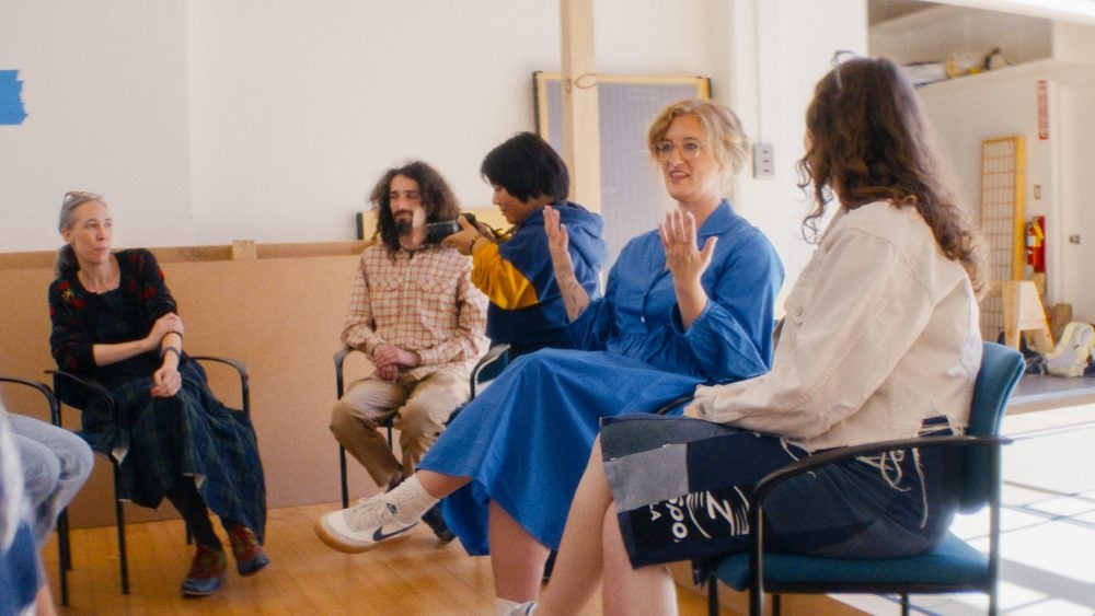 Students and graduate student in a circle chatting