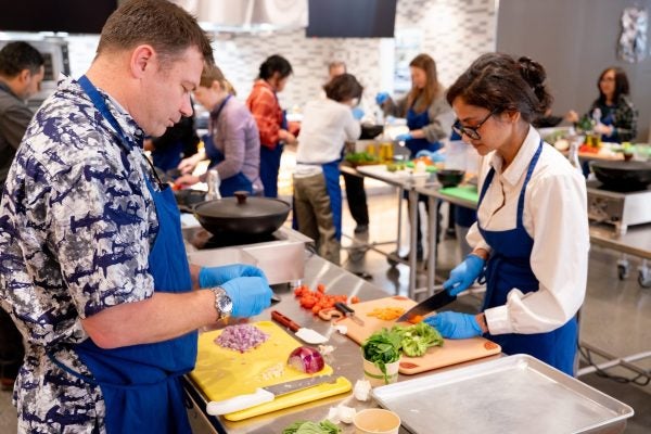 Participants prep ingredients at work stations in the Tipuana Teaching Kitchen