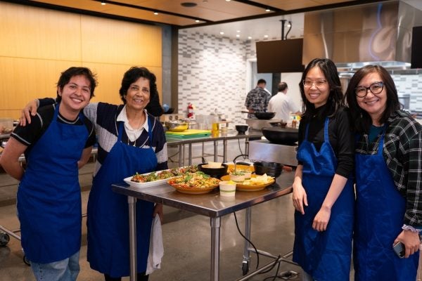 Instructors and graduate students smiling in front of their dishes made in the Tipuana Teaching Kitchen