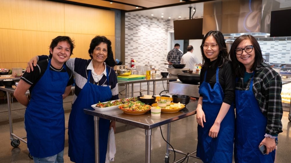 Instructors and graduate students smiling in front of their dishes made in the Tipuana Teaching Kitchen