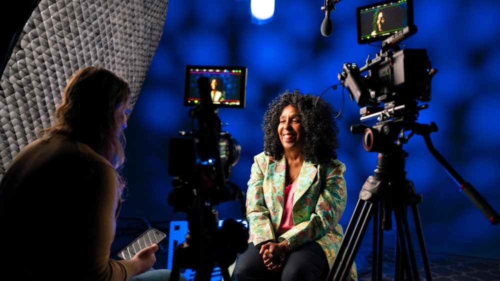 Distinguished Teaching Award winner in conversation with TLC staff member in front of a camera.