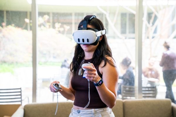 Student wears an Meta VR headset while exploring a virtual world in the Health Equity Lab.